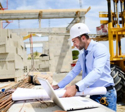 Un home qui regarde des plans sur un chantier de construction. L'électricien intervient durant les phases de construction d'une maison neuve