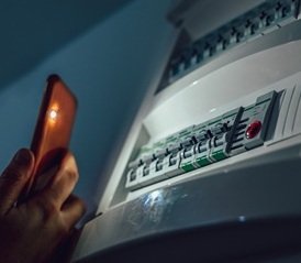Un téléphone qui éclaire un tableau électrique. Intervention rapide en cas de panne de courant ou d'urgence électrique.